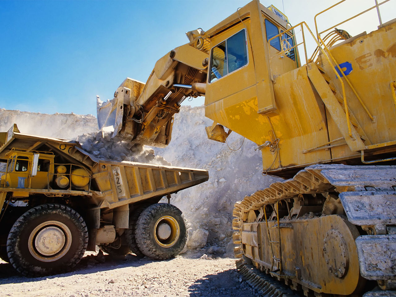 Excavator and dump truck utilizing heavy equipment connectivity at a mining site.