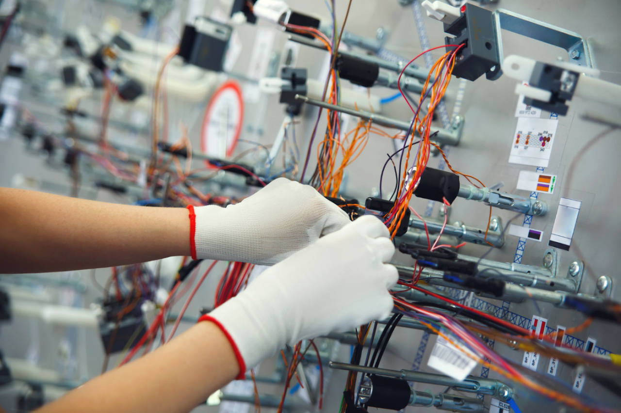 A technician wearing gloves securing wires together for automotive applications. 