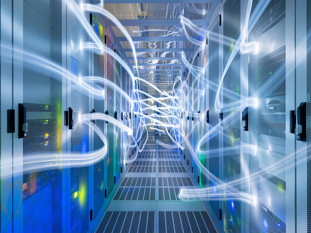 A futuristic data center corridor illuminated by glowing blue and pink light trails, symbolizing high-speed data transfer and connectivity. 