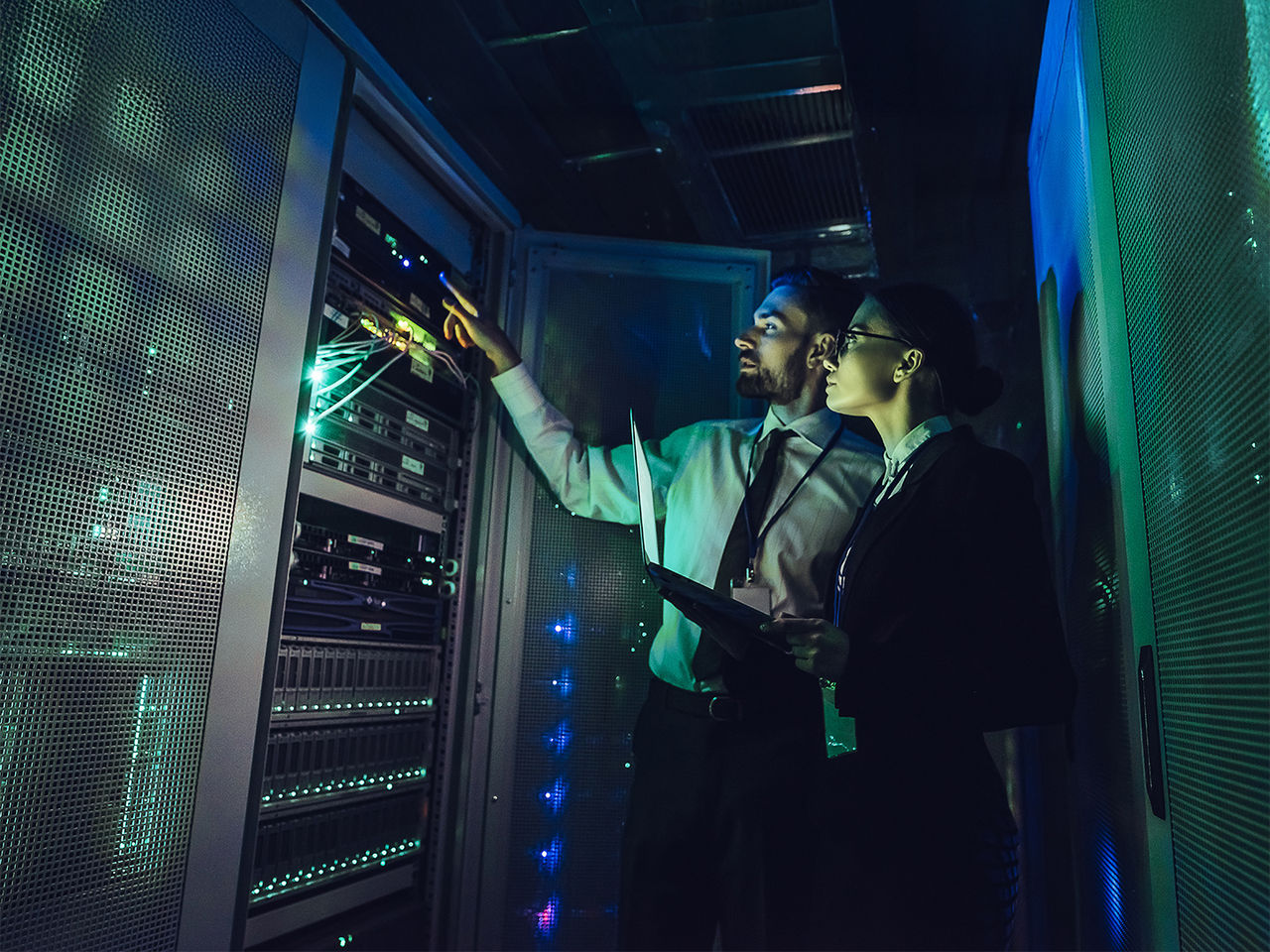 Two engineers examining server equipment in a high-tech data center.