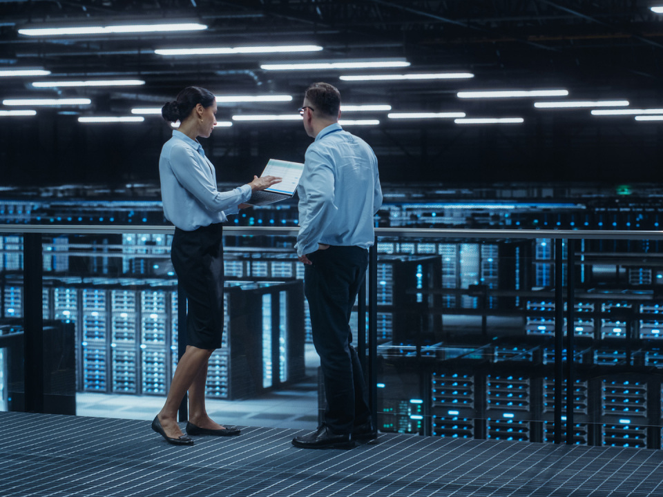 AI data center engineer inspecting liquid cooling manifold with tablet.