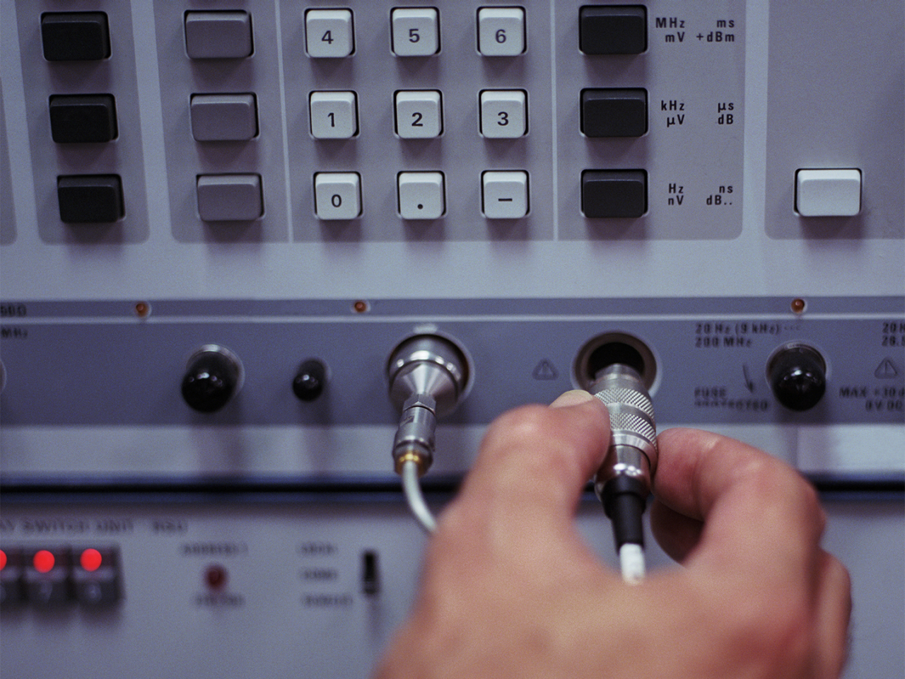 Technician connecting cable to RF test and measurement equipment.