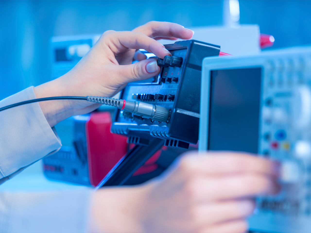 Close up on hand connecting test cables to equipment in a electronics testing lab.